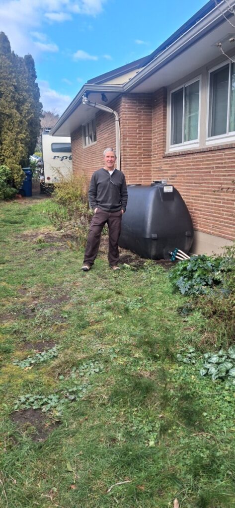 West Seattle homeowner happily showing off rain harvesting project