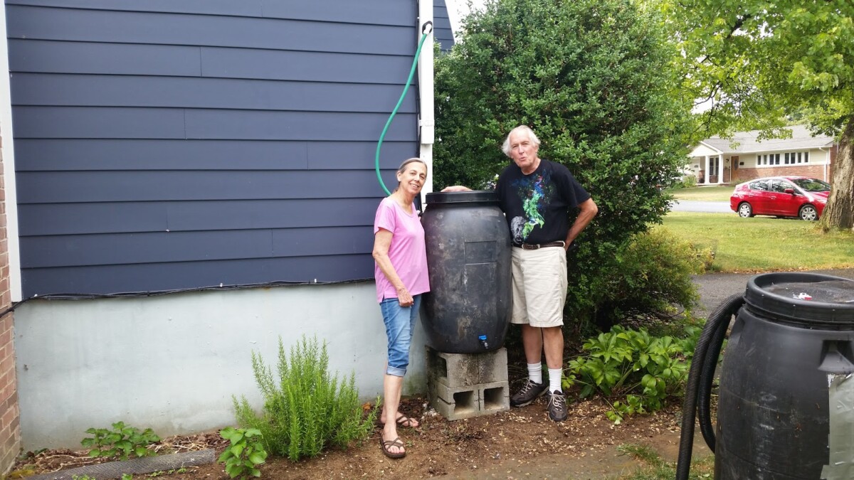 Hero Image Elements - Transforming Traditional Rain Collection Alt Text (125 characters or less) Couple with old rain barrel ready to upgrade to advanced rainwater harvesting systems with hydraulic pressure technology