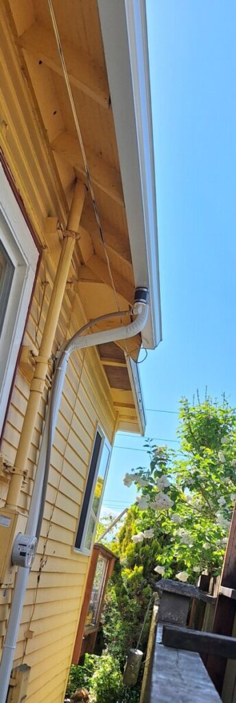 Deviator gutter insert installed between two residential properties showing how the deviator redirects rainwater flow into a remote collection system