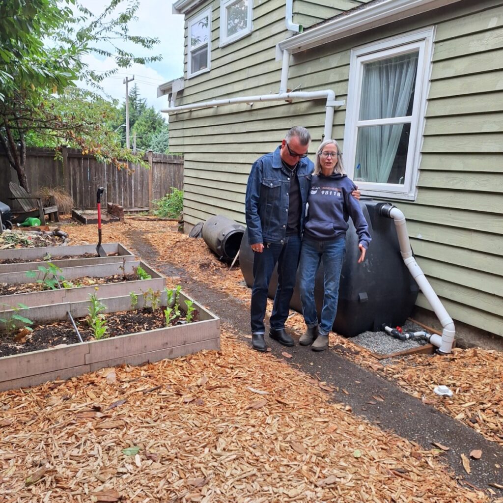 The Johnsons smiling and standing in their backyard next to a lush rain garden and large water cistern, representing their successful participation in Seattle’s RainWise water incentives program