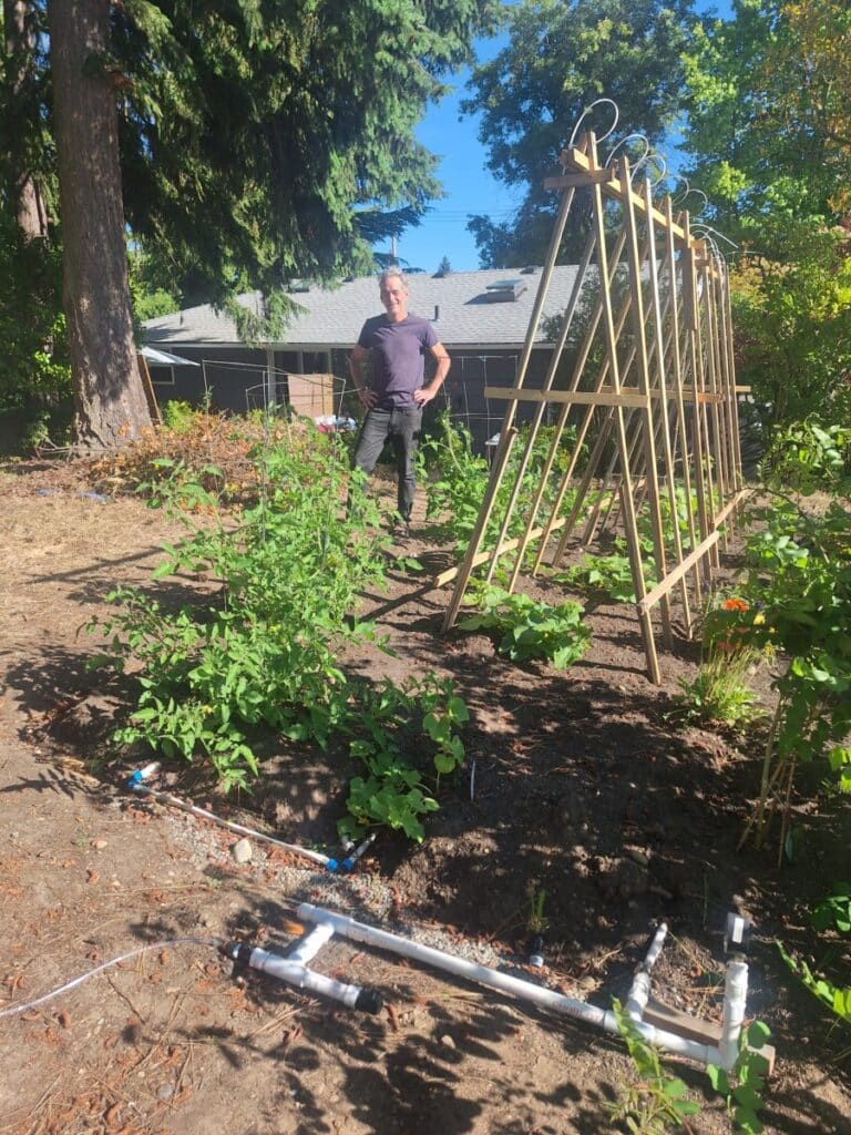 standing in the center of the Product Water demonstration garden, surrounded by Responsive Drip Irrigation (RDI) tape, representing the “Think Outside the Tap” approach to a rainwater-powered, 30% water-saving garden.