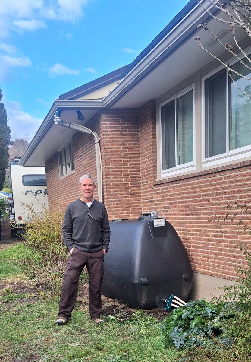 Happy homeowner standing next to raised beds irrigated by rainwater harvesting system